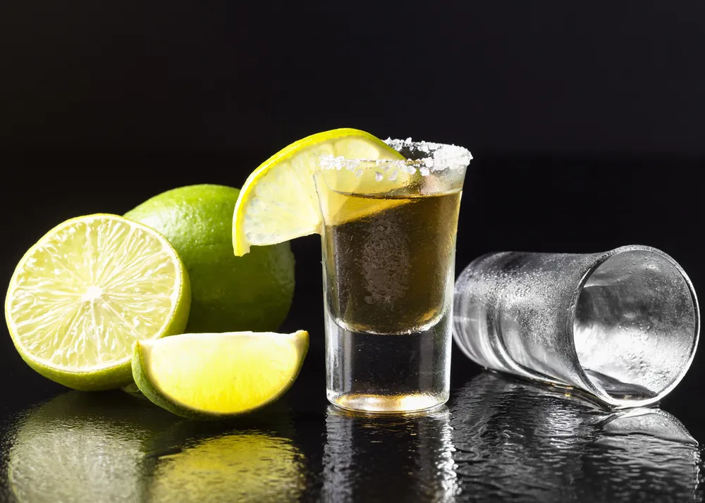 vista-frontal-de-tequila-dorado-con-limon-y-sal