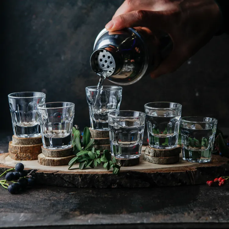 vista-lateral-vasos-de-chupito-con-bebidas-barman-vierte-alcohol